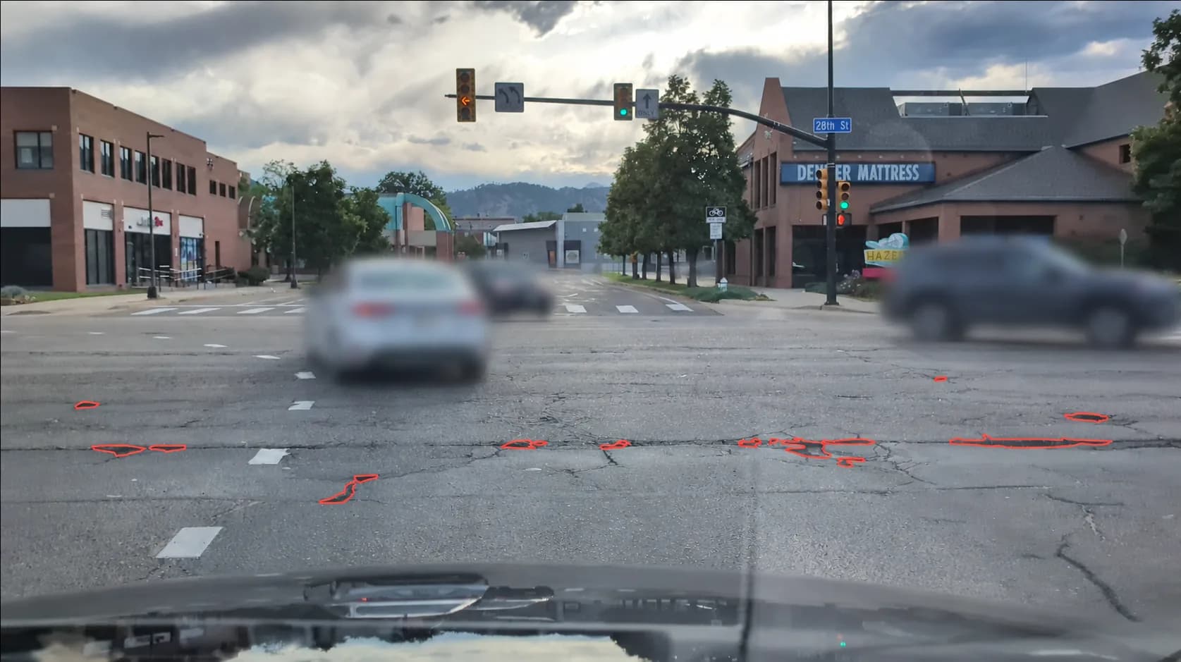 ARTIE capture of a Colorado intersection after the privacy filter has run: every passing vehicle is blurred out while the road, signs and signals stay sharp, and the potholes in the asphalt are outlined in red