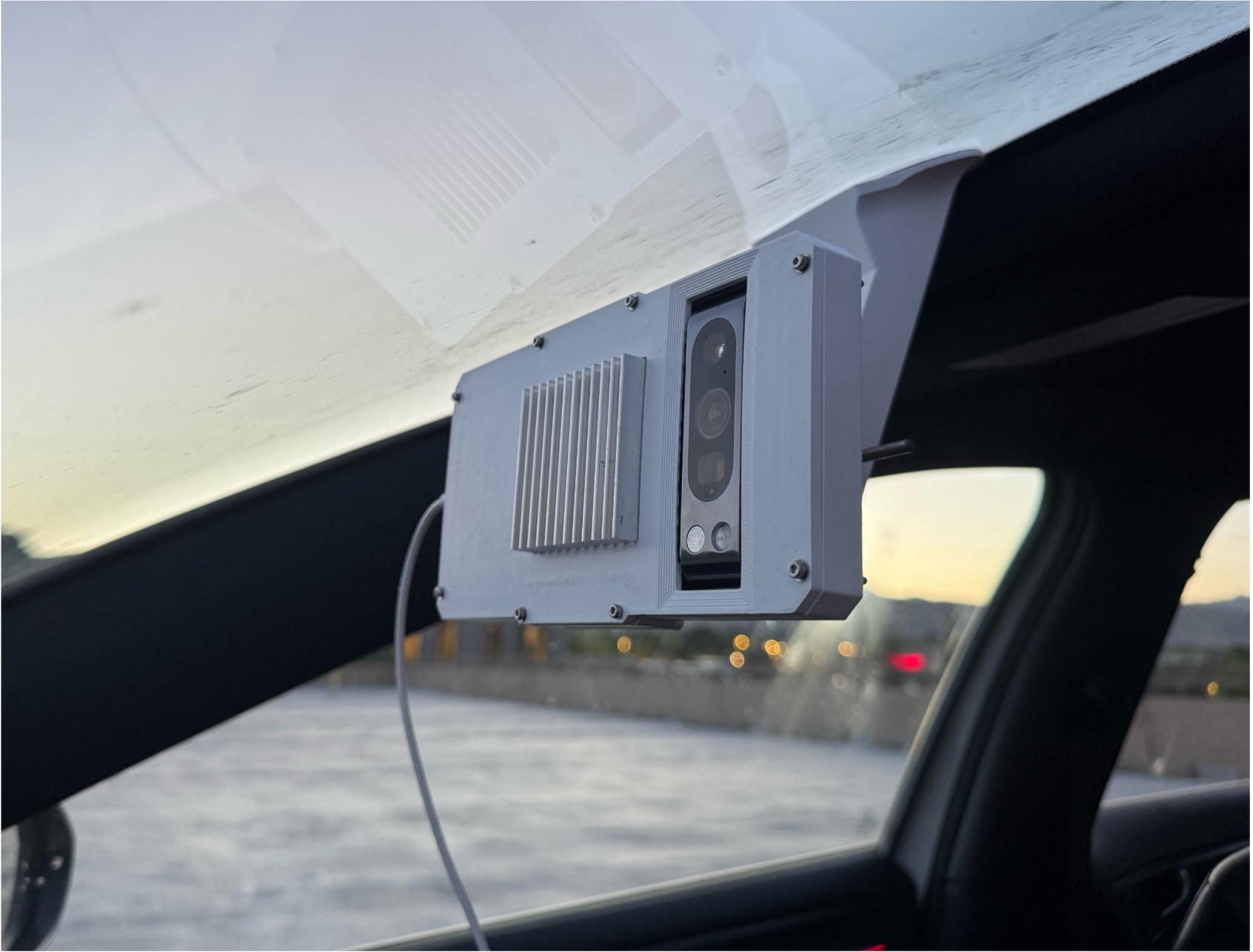 The ARTIE dash camera unit mounted to a vehicle windshield, looking out over a highway