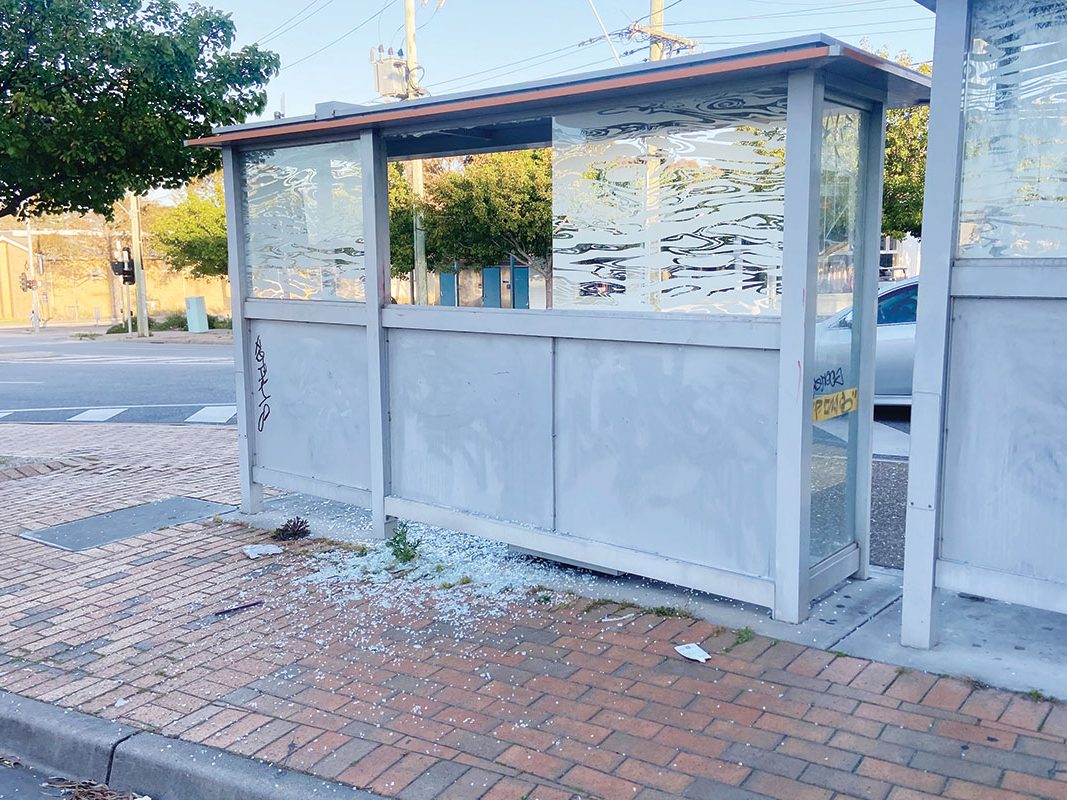 A bus shelter with its glass smashed out and tags sprayed along the panels
